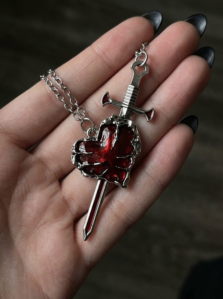 Gothic heart and sword necklace held in hand showing size